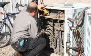 Technician repairing an air conditioning unit outdoors.