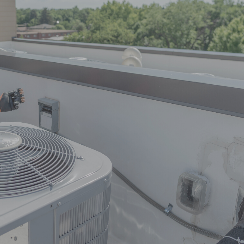 Technician inspecting rooftop commercial HVAC equipment during spring maintenance